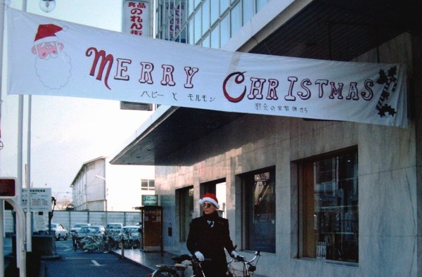 Elder Richard Carroll's banner hangs from the Fuji-shi Papi supermarket store, one vestige of of a very thorough public relations campaign. Elder Lee Richan is wearing Santa hat made by members, similar hats which five Elders also wore throughout December 1977 to proclaim the Christmas message and our goodwill toward the community.
R. Lee  Richan
17 Dec 2005